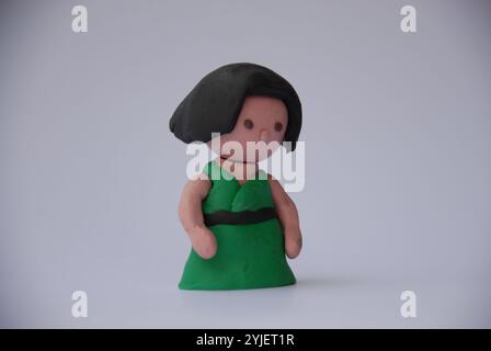 Rendering 3D in argilla stilizzata di giovane donna con capelli scuri e abito verde. Foto Stock