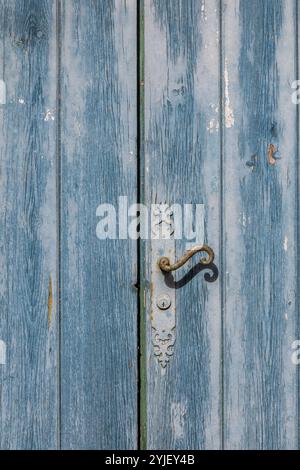 Antica porta blu-verde logorata e maniglia arrugginita, dettagli architettonici esterni Foto Stock