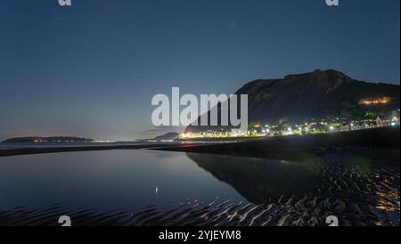 Penmaenmawr Mountain, il semaforo del traffico sulla A55 Expressway in primo piano, vista dalla spiaggia di Llanfairfechan. Immagine scattata nell'ottobre 2024. Foto Stock