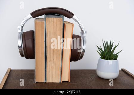 pila di libri con cuffie, apprendimento di lingue straniere con audiobook, apprendimento multimediale, sviluppo di capacità di lettura e ascolto, tecnologia Foto Stock