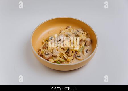 Tagliatelle cremose con funghi e pollo in una ciotola beige su sfondo chiaro Foto Stock