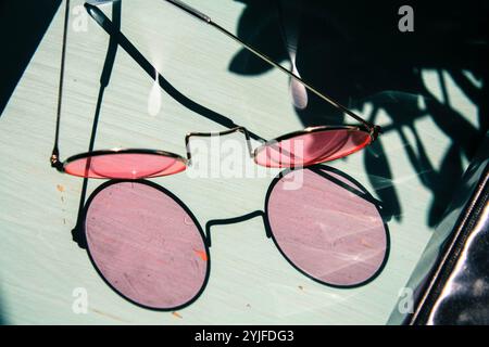 occhiali rosa ombra sulla scrivania blu Foto Stock