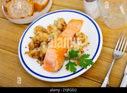 Sul piatto c'è un pezzo di filetto di salmone fritto e contorno di verdure, cavolfiore fritto Foto Stock