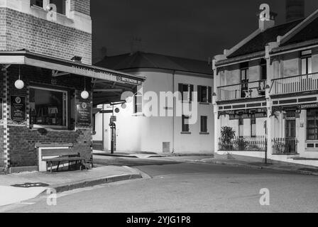 Il sobborgo The Rocks di Sydney, insediato durante la colonizzazione nel 1788, contiene molti monumenti storici ed è il più antico sobborgo dell'Australia. I suoi edifici, le scale e gli archi furono costruiti con arenaria locale, da cui il nome della zona. Fino agli anni '1870 era uno slum dove le "bande di rasoi" si riversavano di notte in vicoli. Oggi è un quartiere turistico ricco di storia circondato da Dawes Point, Millers Point e Barangaroo, spesso considerato parte del distretto di Rocks. Nella foto: Una vista notturna del Palisade Hotel a Millers Point su Bettington Street a Dalgety Road, guardando verso Rodens Lane. Foto Stock