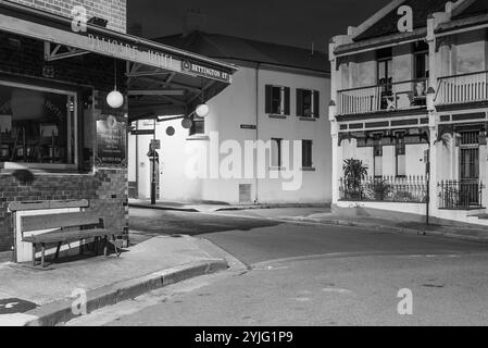 Il sobborgo The Rocks di Sydney, insediato durante la colonizzazione nel 1788, contiene molti monumenti storici ed è il più antico sobborgo dell'Australia. I suoi edifici, le scale e gli archi furono costruiti con arenaria locale, da cui il nome della zona. Fino agli anni '1870 era uno slum dove le "bande di rasoi" si riversavano di notte in vicoli. Oggi è un quartiere turistico ricco di storia circondato da Dawes Point, Millers Point e Barangaroo, spesso considerato parte del distretto di Rocks. Nella foto: Una vista notturna del Palisade Hotel a Millers Point su Bettington Street a Dalgety Road, guardando verso Rodens Lane. Foto Stock