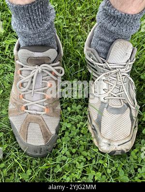 Hai avuto una brutta giornata? Immagine dei piedi di un uomo con calzini grigi e con due diverse scarpe casual all'aperto sull'erba: Una scarpa marrone e una scarpa grigia Foto Stock