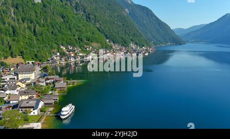 Tranquillo lago di Hallstatt con case colorate immerse nell'acqua e circondate da verdi montagne Foto Stock