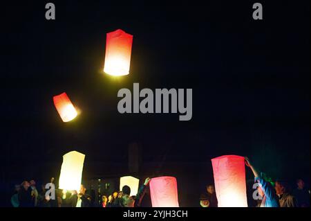 Una vibrante mostra di lanterne rosse e gialle che scivolano silenziosamente attraverso il cielo scuro, creando un'atmosfera incantevole e serena durante una notte fe Foto Stock