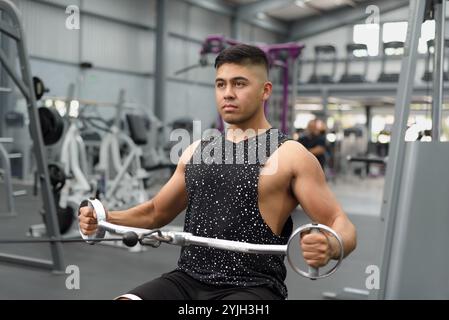 Uomo che si allena alla macchina per cavi in palestra. Un uomo che lavora su una macchina via cavo in una palestra. Foto Stock