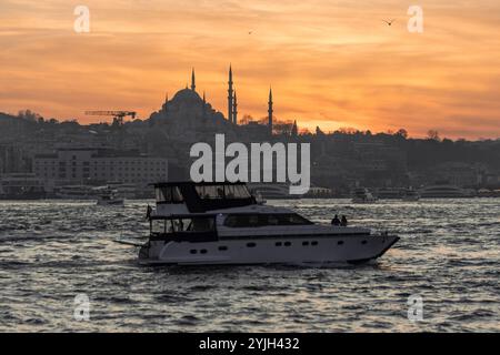 Splendido tramonto alla sagoma del minareto della moschea del Bosforo, barche sull'acqua nella zona Sultanahmet di Istanbul in Turchia Foto Stock