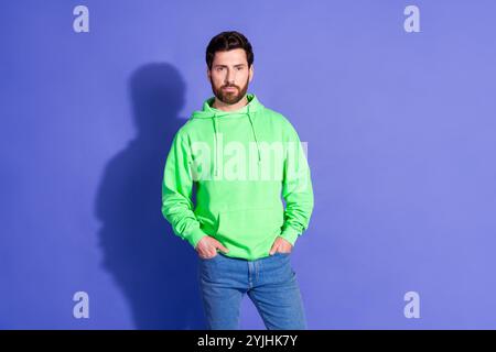 Ritratto fotografico di un giovane modello maschile in posa indossa un abito verde alla moda isolato su sfondo viola Foto Stock