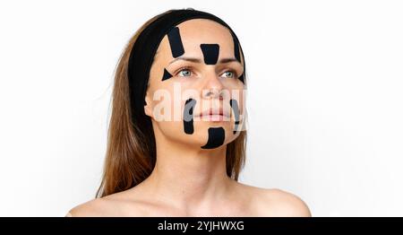 Ritratto di bellezza di una donna caucasica con nastri di kinesiologia nera sul viso. Foto Stock