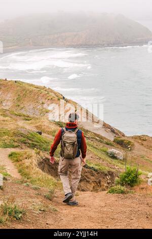 Un escursionista passeggia lungo un sentiero costiero panoramico che si affaccia sull'oceano Foto Stock