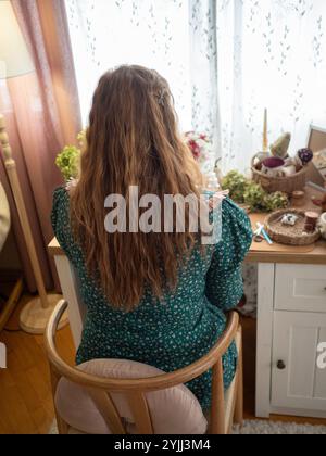 Donna che lavora alla scrivania in una camera accogliente Foto Stock