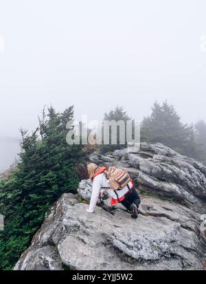 Escursionista che arrampica su un sentiero di montagna in una giornata nebbiosa Foto Stock