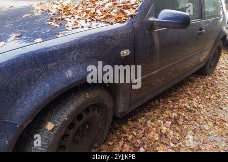 Auto abbandonata ricoperta di foglie autunnali Foto Stock