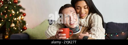 Una coppia si diverte in compagnia, cogliendosi con un drink in un ambiente festoso. Foto Stock