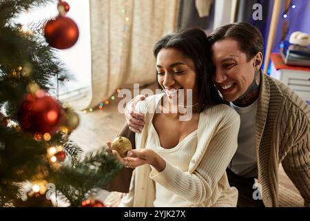 Una coppia si gode un momento tenero insieme, decorando il proprio albero di Natale con allegria natalizia. Foto Stock