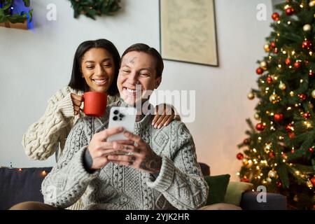 Una coppia gode di momenti di gioia insieme sul divano in mezzo a decorazioni festose. Foto Stock