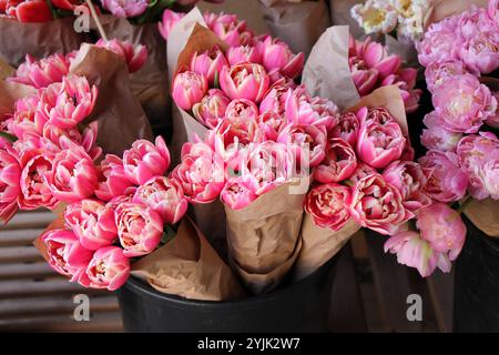 Molte varietà di tulipani in imballaggi di carta per la vendita in un primo piano del mercato dei fiori. Foto Stock