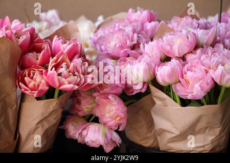 Molte varietà di tulipani in imballaggi di carta per la vendita in un primo piano del mercato dei fiori. Foto Stock