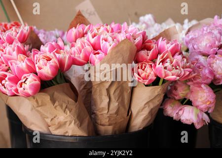 Molte varietà di tulipani in imballaggi di carta per la vendita in un primo piano del mercato dei fiori. Foto Stock