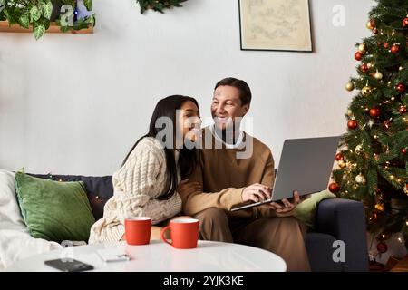 Una coppia amorevole ama passare del tempo insieme mentre navighi su un laptop e sorseggia un drink accogliente. Foto Stock