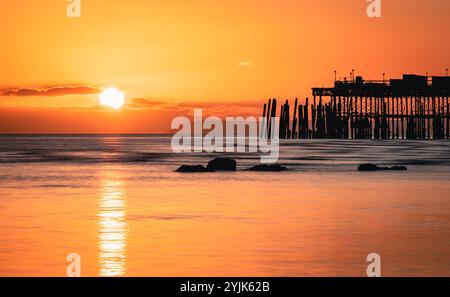 Tramonto con la bassa marea sul lungomare di Hastings, nell'est del Sussex, nell'Inghilterra sud-orientale, Regno Unito Foto Stock