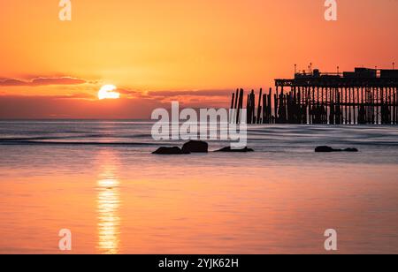 Tramonto con la bassa marea sul lungomare di Hastings, nell'est del Sussex, nell'Inghilterra sud-orientale, Regno Unito Foto Stock