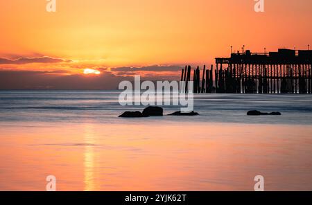 Tramonto con la bassa marea sul lungomare di Hastings, nell'est del Sussex, nell'Inghilterra sud-orientale, Regno Unito Foto Stock