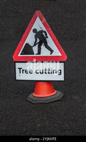 Un segnale triangolare di taglio degli alberi posto sulla strada come avvertimento per i passanti. Foto Stock
