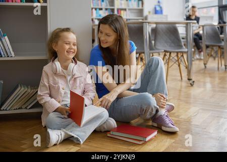 Madre e figlia felici che trascorrono del tempo insieme in biblioteca o in libreria Foto Stock