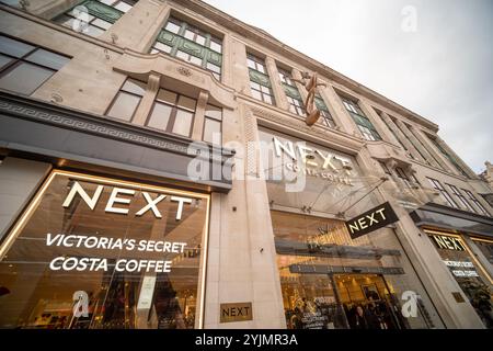 LONDRA - 14 NOVEMBRE 2024: Prossimo flagship store e acquirenti sfocati in movimento su Oxford Street, punto di riferimento per la vendita al dettaglio Foto Stock