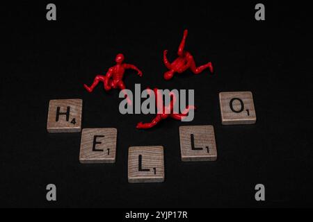 Tre piccole figure rosse da uomo ragno e tessere di lettere in legno con HELLO Word, un saluto mondiale Foto Stock