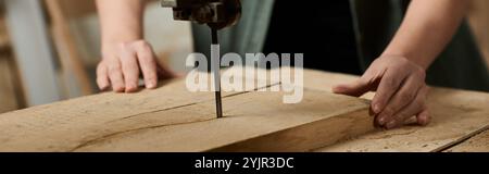 Un falegname di talento si concentra intensamente sulla guida del legno attraverso uno strumento di taglio in un'atmosfera vivace di officina. Foto Stock