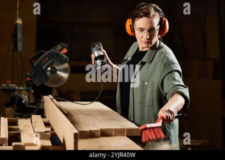 Nel suo laboratorio, una talentuosa falegnameria femminile si concentra sulla modellatura del legno gestendo sapientemente i suoi utensili. Foto Stock