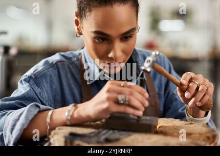 Un abile artigiano disegna minuziosamente gioielli mentre è circondato da strumenti e gemme. Foto Stock