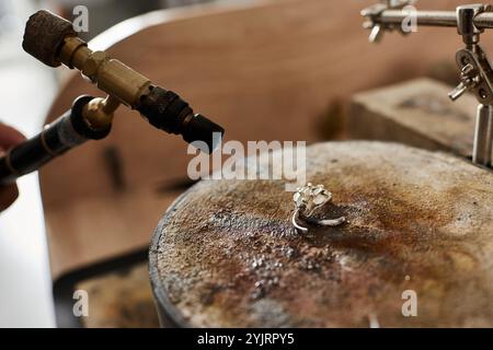 Un talentuoso artigiano crea sapientemente uno splendido anello gioiello in un ambiente creativo. Foto Stock