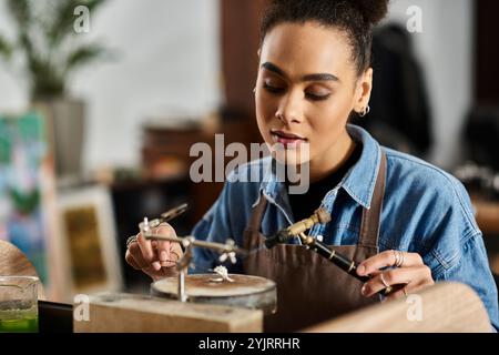 Una donna di talento si concentra intensamente sulla creazione di gioielli intricati con le sue mani esperte Foto Stock