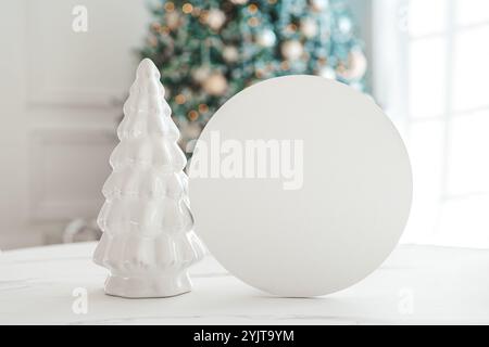 Abete in ceramica bianco decorativo e scheda vuota rotonda per testo sullo sfondo dell'albero di Natale. Cerchio bianco vuoto con spazio di copia. Festivo Foto Stock