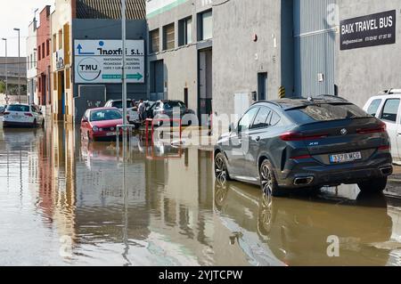 Viladecans. Spagna - 15 novembre 2024: Forti piogge hanno causato l'inondazione di una strada, sommergendo veicoli fino alle ruote. Questa immagine illustra il dram Foto Stock