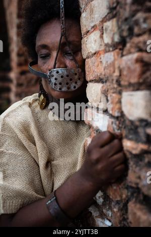 Donna nera incatenata e con una maschera di ferro sulla bocca, che rappresenta la schiava Anastacia sulle pareti di mattoni di Pelourinho. Schiavitù in Brasile. Sufferin Foto Stock