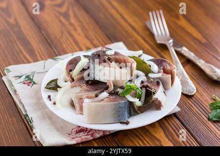 sgombro leggermente salato con cipolle e spezie, in un piatto su un tavolo di legno. Foto Stock