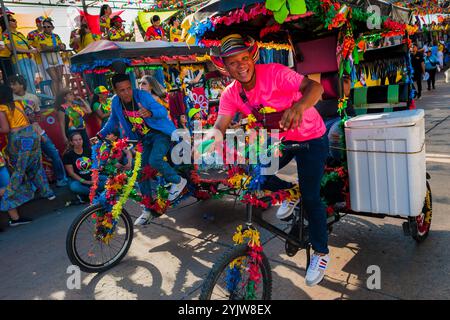 I ciclisti colombiani, in sella a biciclette ornate, partecipano alla Batalla de Flores, la principale parata del Carnevale di Barranquilla, Colombia. Foto Stock