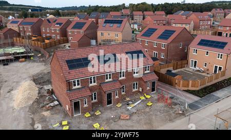 Il tetto di una fila di case di nuova costruzione su un cantiere in costruzione con tetto integrato o pannelli solari a tetto per un costo economico e sostenibile Foto Stock