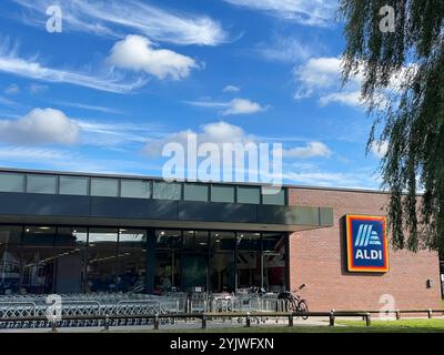 Manchester, Regno Unito, 4 ottobre 2024. Segno commerciale di ALDI Store contro un cielo blu con nuvola bianca. ALDI è il marchio comune di due superma sconto tedesco Foto Stock