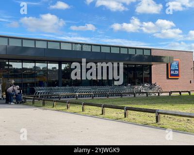 Manchester, Regno Unito, 4 ottobre 2024. Segno commerciale di ALDI Store contro un cielo blu con nuvola bianca. ALDI è il marchio comune di due superma sconto tedesco Foto Stock