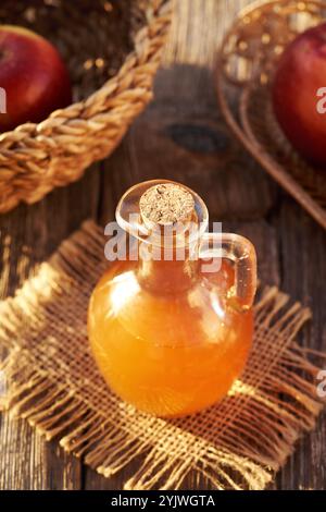Aceto di sidro di mele non filtrato con frutta fresca su un tavolo alla luce del sole Foto Stock