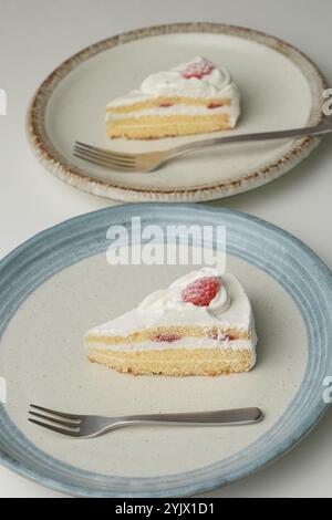 Shortcake e forchetta di fragole giapponesi su ogni piatto grande e piccolo su un tavolo bianco. Foto Stock