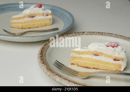 Shortcake e forchetta di fragole giapponesi su ogni piatto grande e piccolo su un tavolo bianco. Foto Stock